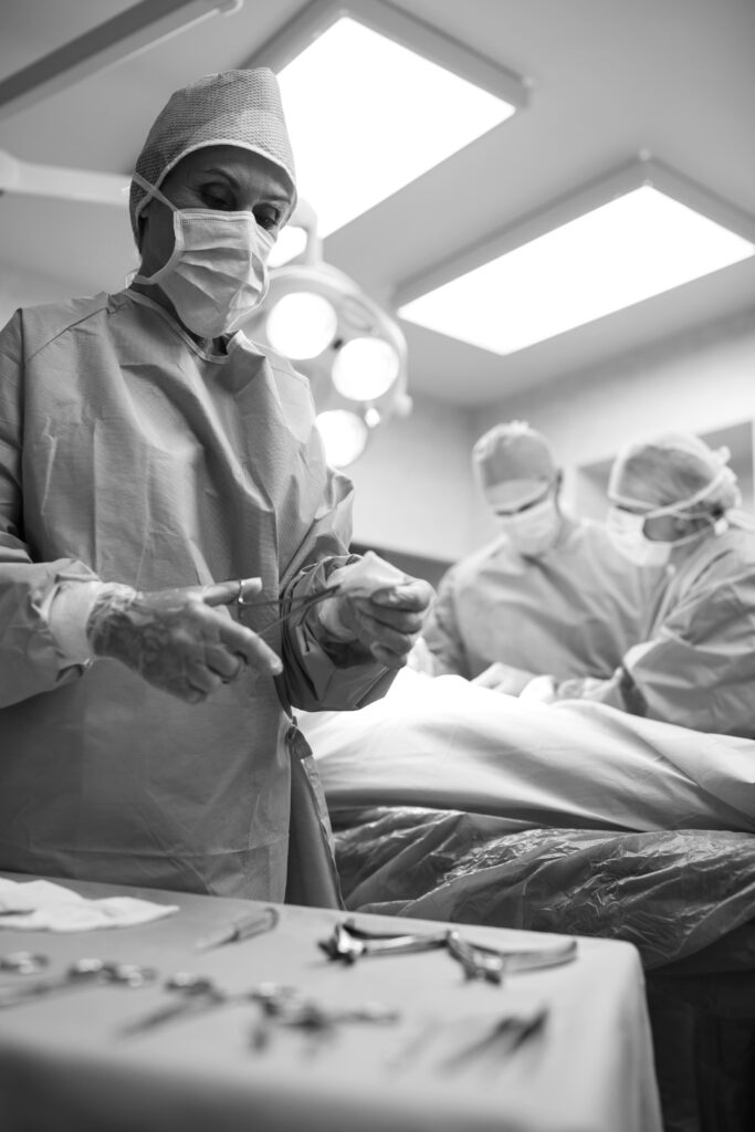 Surgeon holding surgical tool while colleagues performing operation